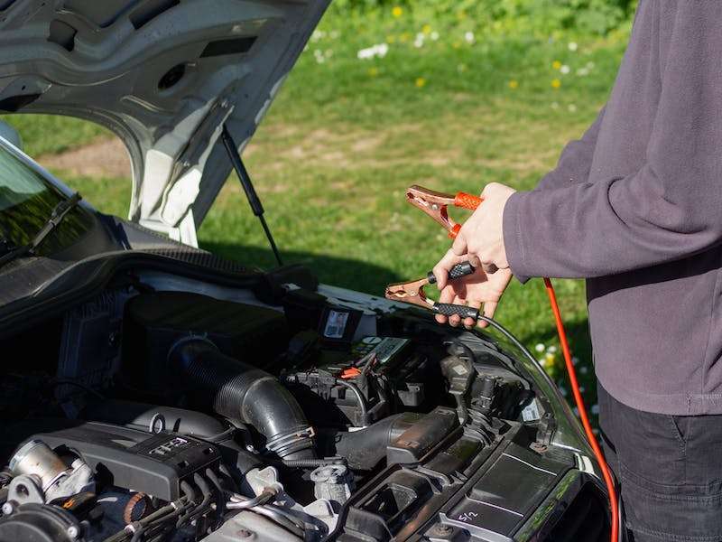 Holding jumper cables over a car engine